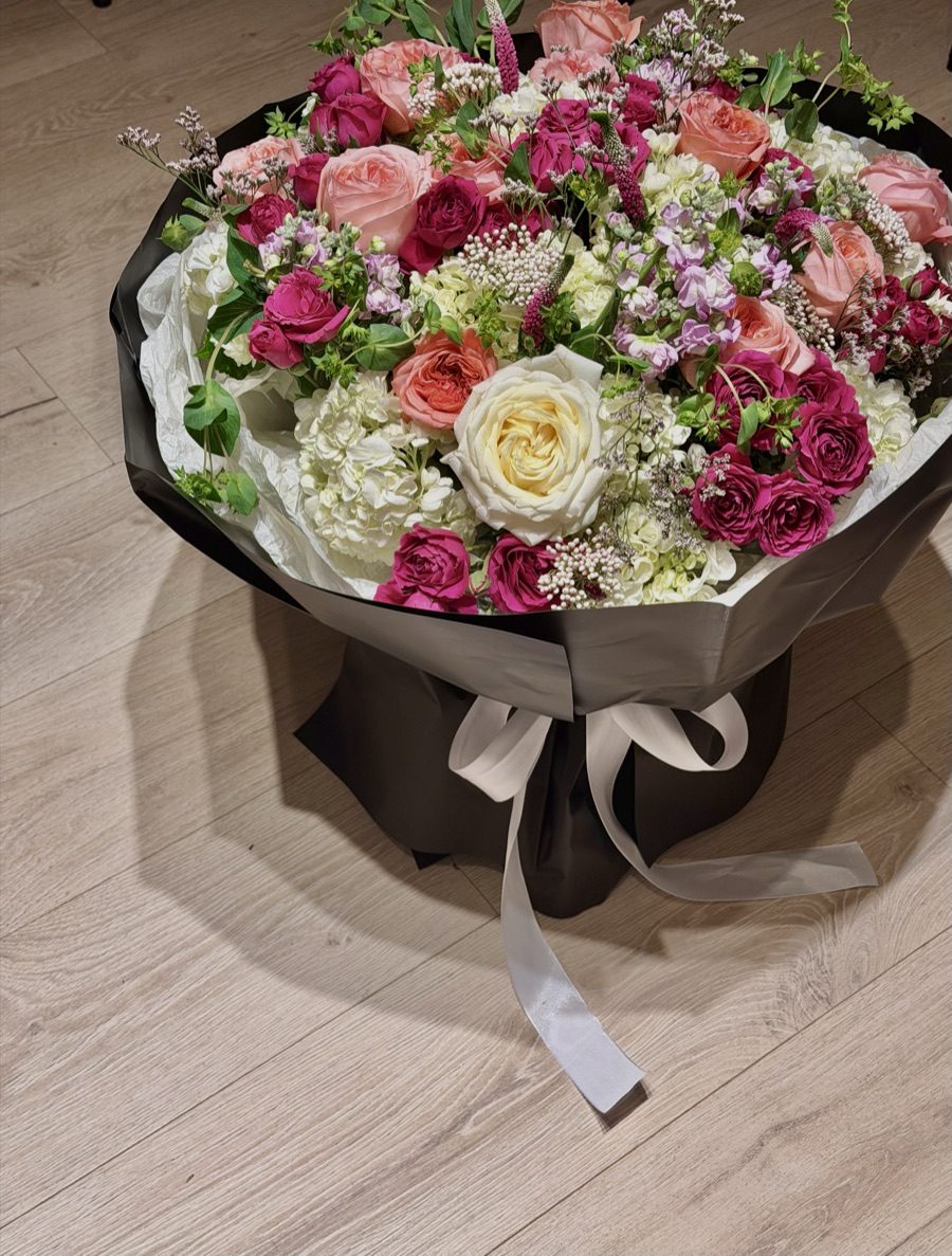 Blush, cream and magenta rose bouquet in black Liebe Blüme wrapping with white satin ribbon