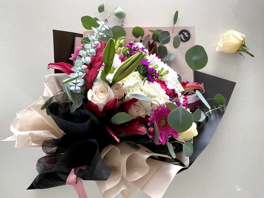 Lily, rose and gerbera bouquet with eucalyptus in black and cream Liebe Blüme wrap, flat lay